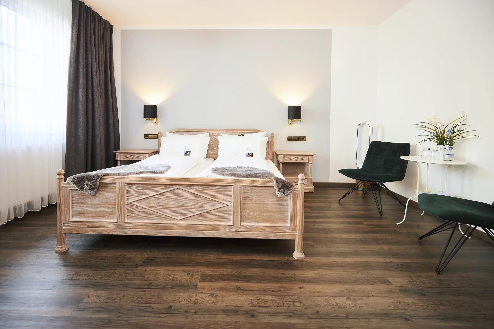 Komfortzimmer mit hellem Holzdoppelbett und dunkelgrüner Sitzgruppe